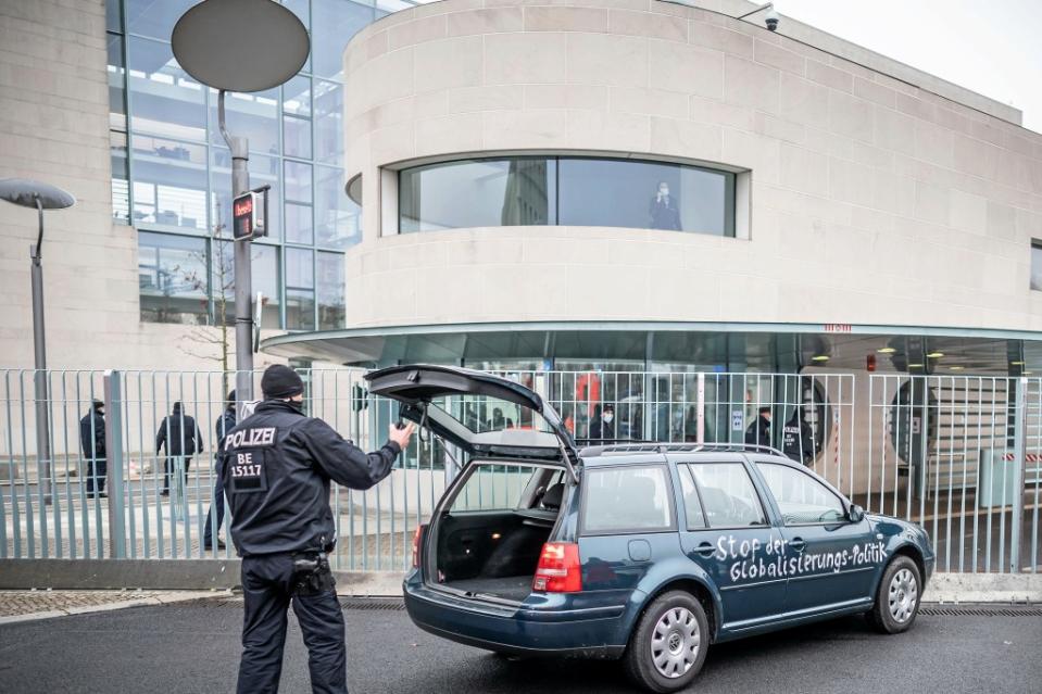 Ein Polizist steht vor dem Kanzleramt an der offenen Heckklappe eines Autos, das zuvor gegen das Tor des Bundeskanzleramts gefahren war, und blickt in den Kofferraum. Auf einer Tür des Fahrzeugs ist die Aufschrift "Stop der Globalisierungs-Politik" zu lesen.<span class="copyright">Michael Kappeler / dpa</span>