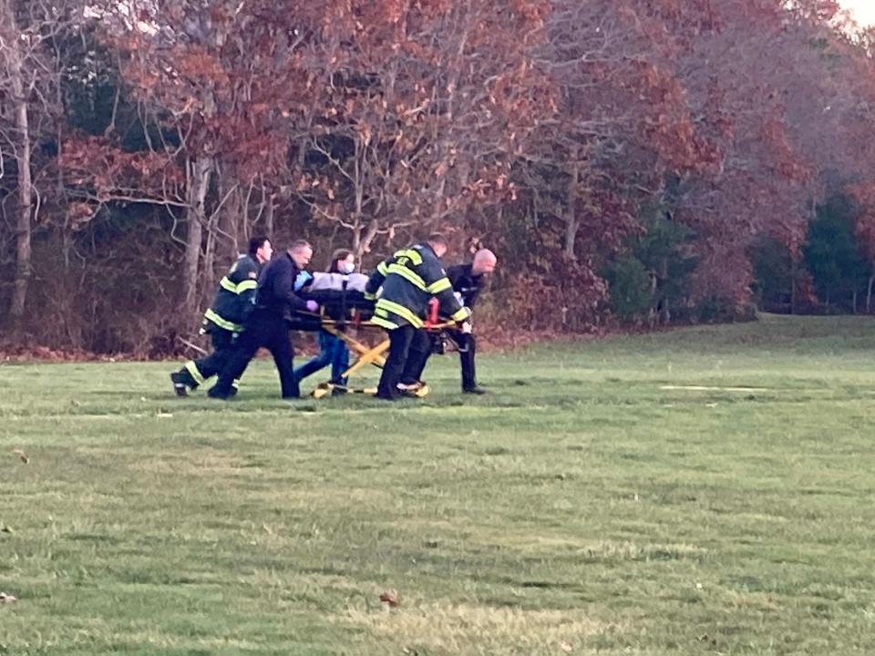 Rescuers bring an injured person to a waiting medical helicopter after a plane crash on Friday at the Falmouth Airpark in East Falmouth.