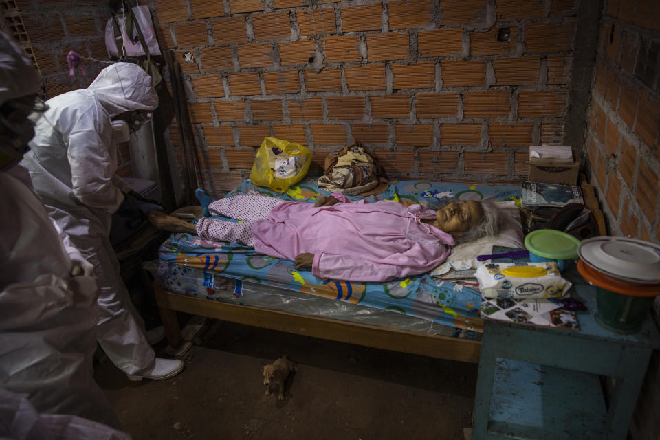 Miembros de un equipo gubernamental se preparan para retirar el cadáver de Cruz Amanda Vargas, quien murió por síntomas relacionados con el coronavirus a los 84 años, en su casa de la comunidad indígena Shipibo en Pucallpa, en la región peruana de Ucayali, el 31 de agosto de 2020. En el apogeo del brote en mayo y junio, alrededor de 15 personas fallecían a diario, dijo Juan Carlos Salas, director de la agencia de salud de la región de Ucayali. (AP Foto/Rodrigo Abd)