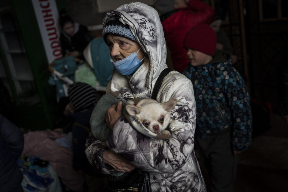 An elderly woman and her pet wait for a train (Bernat Armangue / AP)