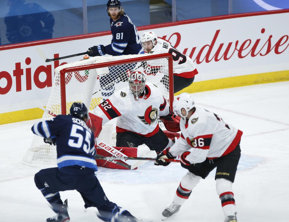 Ottawa Senators goaltender Filip Gustafsson (32) saves a shot from Winnipeg Jets' Mark Scheifele (55) as Senators' Colin White (36) defends during first-period NHL hockey game action in Winnipeg, Manitoba, Saturday, May 8, 2021. (John Woods/The Canadian Press via AP)