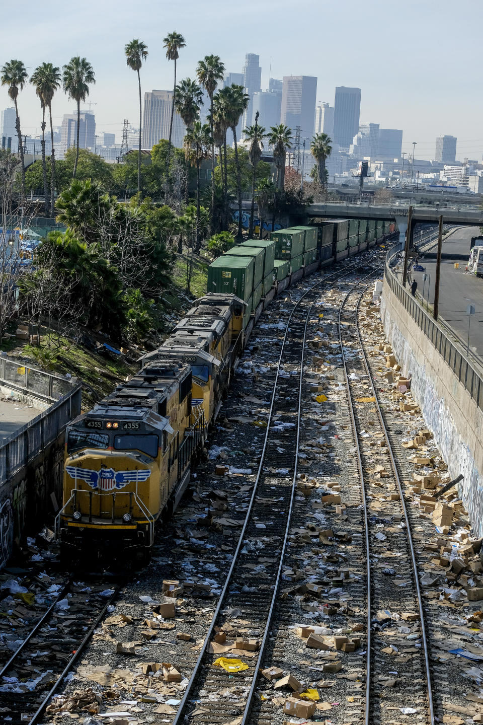 A train passes by as shredded boxes and packages at a section of the Union Pacific train tracks in downtown Los Angeles Friday, Jan. 14, 2022. Thieves have been raiding cargo containers aboard trains nearing downtown Los Angeles for months, leaving the tracks blanketed with discarded packages. The sea of debris left behind included items that the thieves apparently didn't think were valuable enough to take, CBSLA reported Thursday. (AP Photo/Ringo H.W. Chiu)
