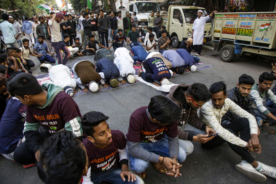 Muslim youth cordon a place as others pray during a protest rally against a new citizenship law, in Kolkata, India, Tuesday, Jan. 21, 2020. India has been embroiled in protests since December, when Parliament passed a bill amending the country's citizenship law. The new law provides a fast track to naturalization for some migrants who entered the country illegally while fleeing religious persecution. But it excludes Muslims, which critics say is discriminatory and a violation of India's Constitution. (AP Photo/Bikas Das)