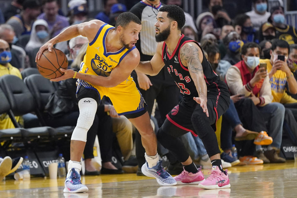 Golden State Warriors guard Stephen Curry, left, is defended by Toronto Raptors guard Fred VanVleet during the first half of an NBA basketball game in San Francisco, Sunday, Nov. 21, 2021. (AP Photo/Jeff Chiu)