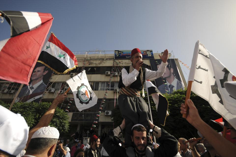 Supporters of Syria's President Bashar al-Assad wave the national flags and chant slogans in front of General Federation of Trade Unions building, during presidential election in Damascus June 3, 2014. (REUTERS/Omar Sanadiki)