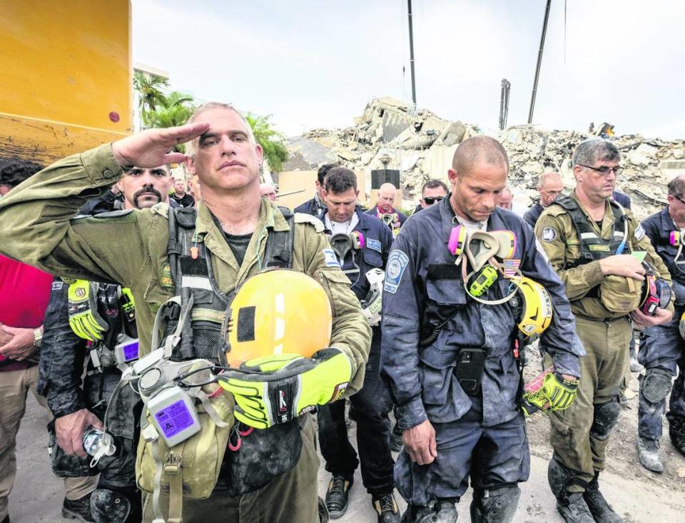 Surfside, Florida, 7 de julio de 2021 – Un miembro del equipo de búsqueda y rescate israelí (izquierda) saluda frente a los escombros de lo que fueron las Champlain Towers South durante una ceremonia de oración. Miembros de los equipos de búsqueda y rescate y de los bomberos de Miami-Dade, junto con la policía y los trabajadores que estuvieron trabajando en el lugar del derrumbe, se reunieron para un momento de oración y silencio junto a la torre derrumbada.