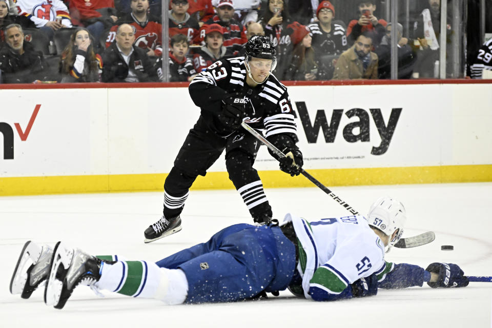 CORRECTS MONTH TO FEB. NOT JAN. - New Jersey Devils left wing Jesper Bratt (63) passes the puck by Vancouver Canucks defenseman Tyler Myers (57) during the second period of an NHL hockey game, Monday, Feb. 6, 2023, in Newark, N.J. (AP Photo/Bill Kostroun)