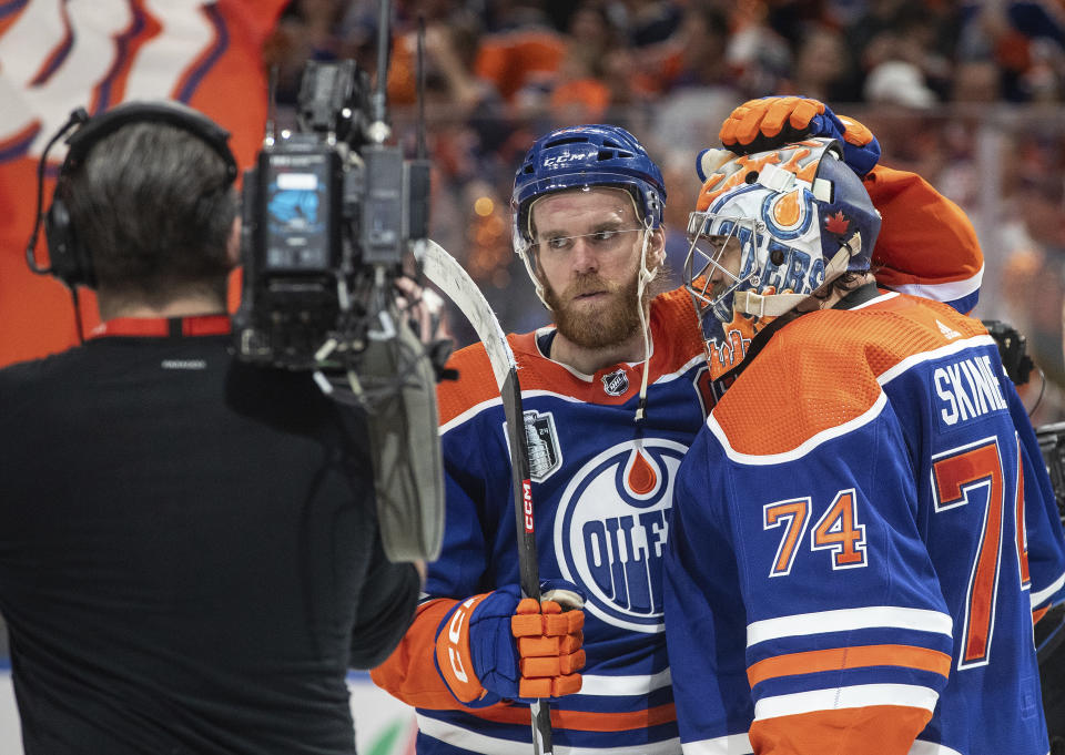 Edmonton Oilers' Connor McDavid (97) and goalie Stuart Skinner (74) celebrate the team's win over the Florida Panthers in Game 4 of the NHL hockey Stanley Cup Final, Saturday, June 15, 2024, in Edmonton, Alberta. (Jason Franson/The Canadian Press via AP)