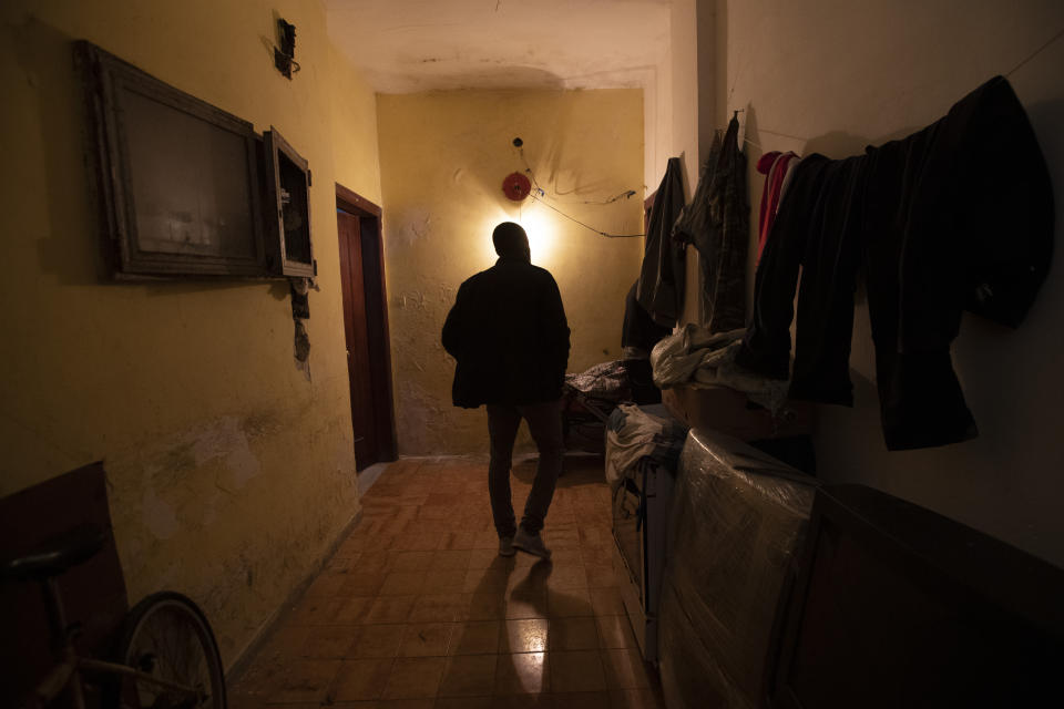 In this photo taken on Monday, April 27, 2020, Appiah Kwasi, a cultural mediator from Ghana, enters the home where 46 men, from Nigeria and Ghana live, in Castel Volturno, near Naples, Southern Italy. The home has no running water, the dilapidated electrical system doesn't reach many rooms that are in the dark. They are known as “the invisibles,” the undocumented African migrants who, even before the coronavirus outbreak plunged Italy into crisis, barely scraped by as day laborers, prostitutes and seasonal farm hands. Locked down for two months in their overcrowded apartments, their hand-to-mouth existence has grown even more precarious with no work, no food and no hope. (AP Photo/Alessandra Tarantino)