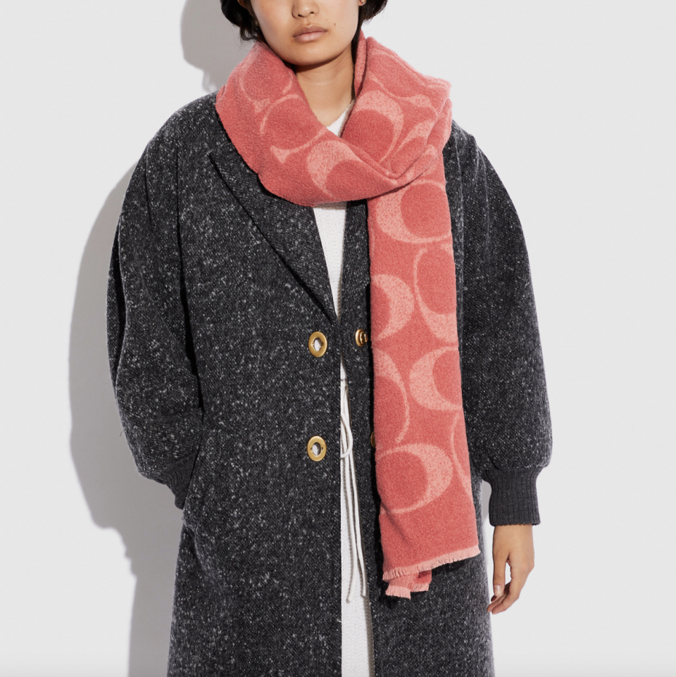 model in black coat and pink coach Reversible Signature Muffler (Photo via Coach)