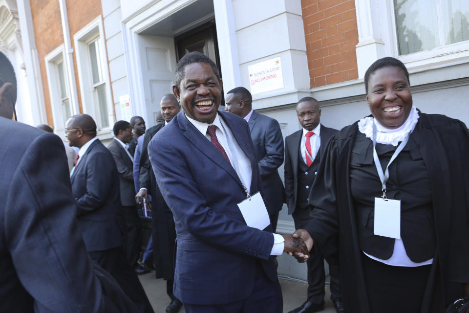 Lawyers representing Zimbabwean President Emmerson Mnangagwa celebrate after the Constitutional Court upheld his narrow victory in Harare, Friday, Aug. 24, 2018. Zimbabwe's constitutional court on Friday unanimously upheld President Emmerson Mnangagwa's narrow victory in last month's historic election after the opposition alleged vote-rigging, saying "sufficient and credible evidence" had not been produced. (AP Photo/Tsvangirayi Mukwazhi)