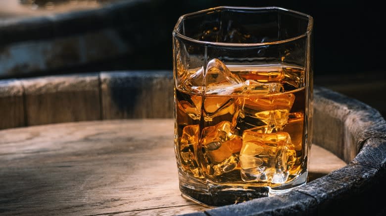 A glass of whiskey on a wooden barrel