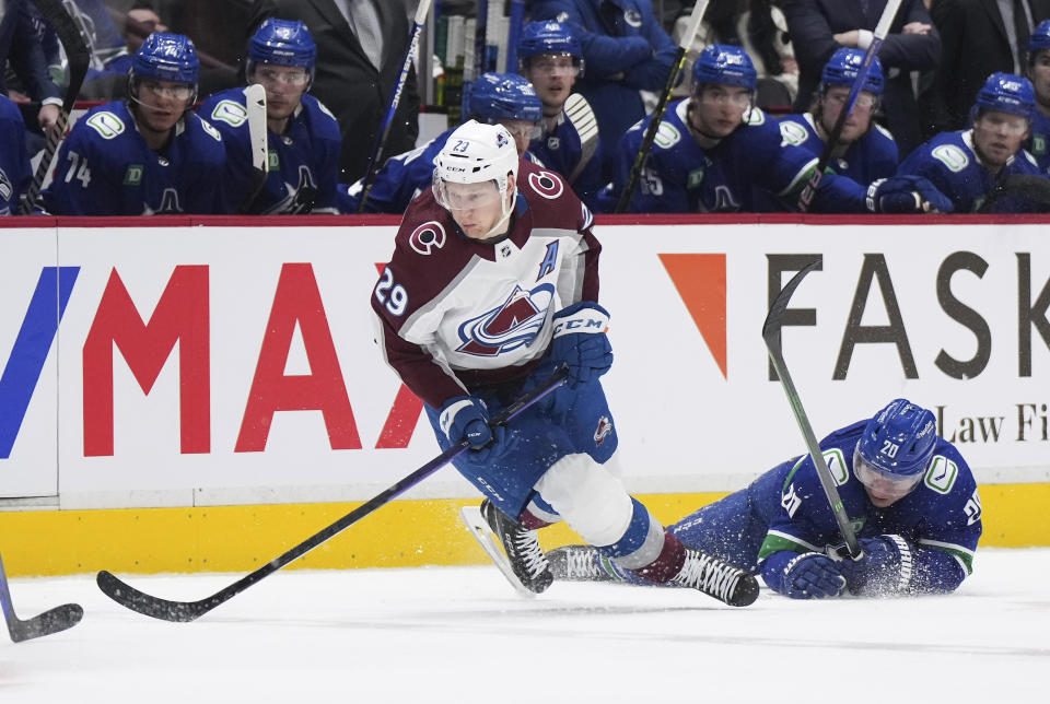 Colorado Avalanche's Nathan MacKinnon (29) falls next to Vancouver Canucks' Curtis Lazar (20) during the second period of an NHL hockey game Thursday, Jan. 5, 2023, in Vancouver, British Columbia. (Darryl Dyck/The Canadian Press via AP)