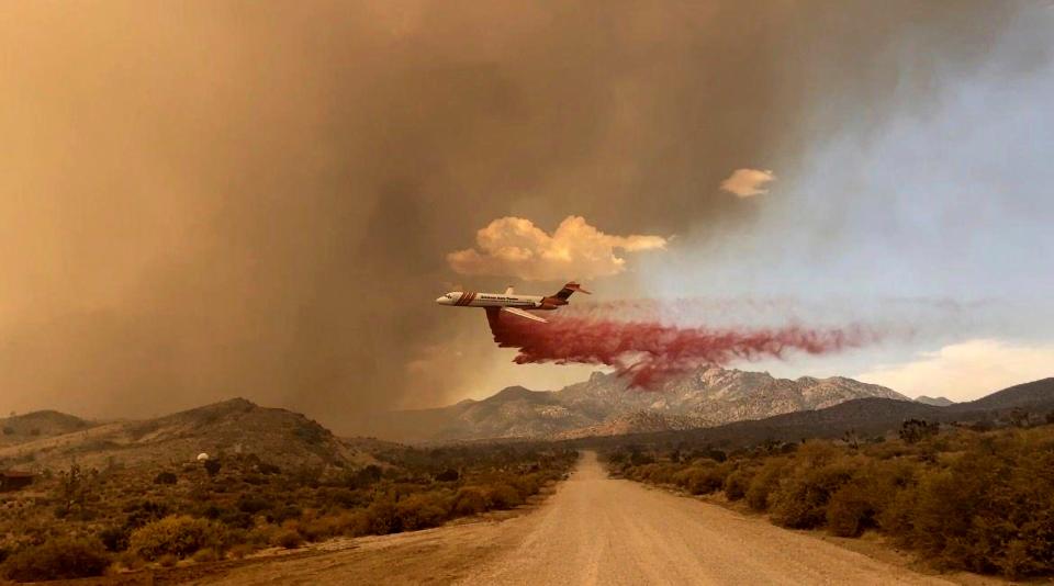 This photo provided by the National Park Service Mojave National Preserve shows a tanker making a fire retardant drop over the York fire in Mojave National Preserve on Saturday, July 29, 2023. A massive wildfire burning out of control in California's Mojave National Preserve is spreading rapidly amid erratic winds. Meanwhile, firefighters reported some progress Sunday against another major blaze to the southwest that prompted evacuations. (Park Ranger R. Almendinger/ InciWeb /National Park Service Mojave National Preserve via AP)
