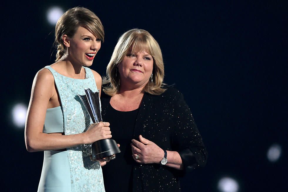 Taylor Swift holding an award while standing next to her mother.