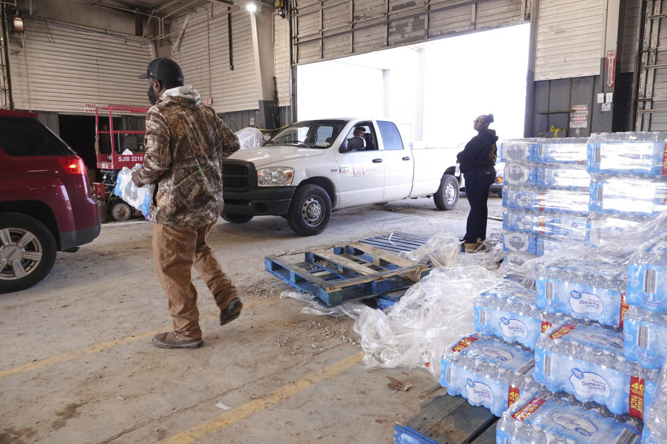 Phillips County employees distribute water for people without water Tuesday, Jan. 30, 2024, in Helena, Arkansas. Parts of the east Arkansas town has been without water for two weeks after the state was hit by below freezing temperatures, and residents have been lining up for jugs of water and a truck of mobile showers dispatched to the community. (AP Photo/Karen Pulfer Focht)