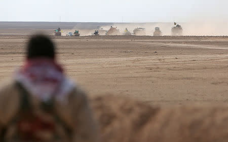 A Syrian Democratic Forces (SDF) fighter watches a convoy of his forces advancing in the north of Raqqa city, Syria. REUTERS/Rodi Said