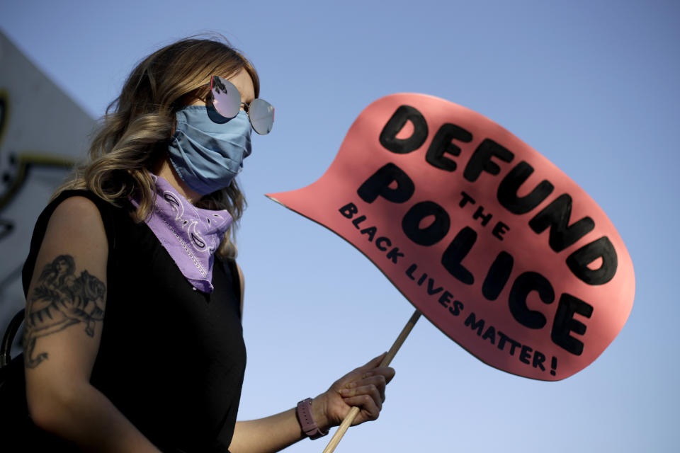 FILE - A demonstrator holds a sign calling for the defunding of the Kansas City, Mo. Police Department during a rally in Kansas City, Mo., Saturday, June 13, 2020, to protest the death of George Floyd. Leaders in largely Democratic Kansas City, Missouri, don't control the city's police department, hire the police chief or determine how the department spends its tax dollars. A 1930s-era law gives that power to a five-member board largely appointed by the Missouri governor, who since 2017 has been a Republican. (AP Photo/Charlie Riedel, File)