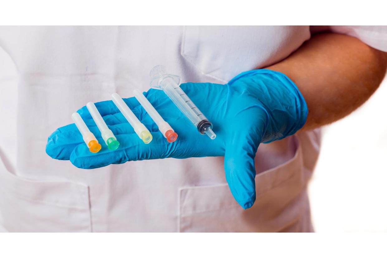 Doctor hand with latex glove holding multiple syringes