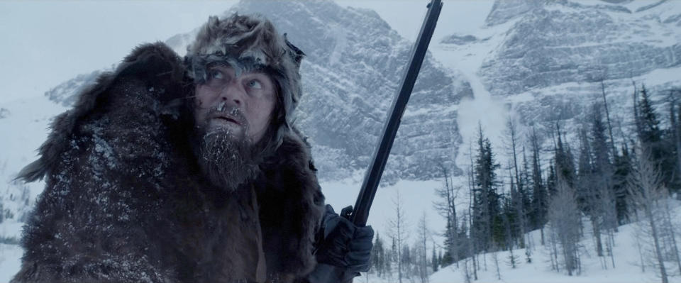 Leonardo DiCaprio as Hugh Glass, in fur attire, gripping a rifle in a snowy terrain from the movie "The Revenant"