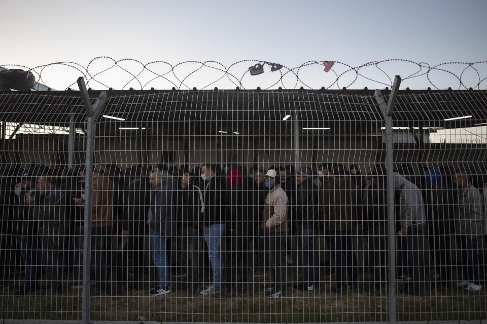 Palestinian workers line up while waiting at the Palestinian side of Erez crossing to cross into Israel, in the town of Beit Hanoun, northern Gaza Strip, Sunday, March. 27, 2022. Israel said it will reopen its crossing with the Gaza Strip to Palestinian workers on Tuesday, April 26, 2022, after it had been closed for several days following rocket attacks from the Palestinian enclave. Israel has issued thousands of work permits to Palestinians from Gaza, which has been under a crippling Israeli and Egyptian blockade since Hamas seized power from rival Palestinian forces nearly 15 years ago. (AP Photo/Khalil Hamra)