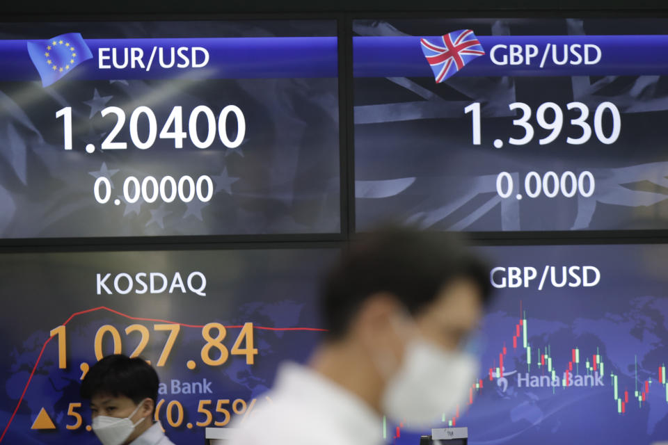 Currency traders walk near screens showing the Korean Securities Dealers Automated Quotations (KOSDAQ), left, and the foreign exchange rates at the foreign exchange dealing room of the KEB Hana Bank headquarters in Seoul, South Korea, Thursday, April 22, 2021. Asian shares were higher on Thursday after a broad advance on Wall Street led by technology companies and banks. (AP Photo/Lee Jin-man)