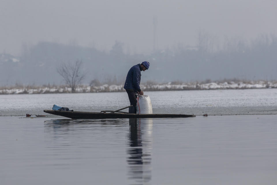 A wildlife worker Mohd Ashraf opens a bag of paddy to spread on the frozen surface of a wetland in Hokersar, north of Srinagar, Indian controlled Kashmir, Friday, Jan. 22, 2021. Wildlife officials have been feeding birds to prevent their starvation as weather conditions in the Himalayan region have deteriorated and hardships increased following two heavy spells of snowfall since December. Temperatures have plummeted up to minus 10-degree Celsius (14 degrees Fahrenheit). (AP Photo/Dar Yasin)
