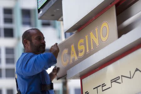 A worker removes the casino sign of the Condado Plaza Hotel after a spokesman announced that the casino is closing, in San Juan, Puerto Rico July 22, 2015. REUTERS/Alvin Baez