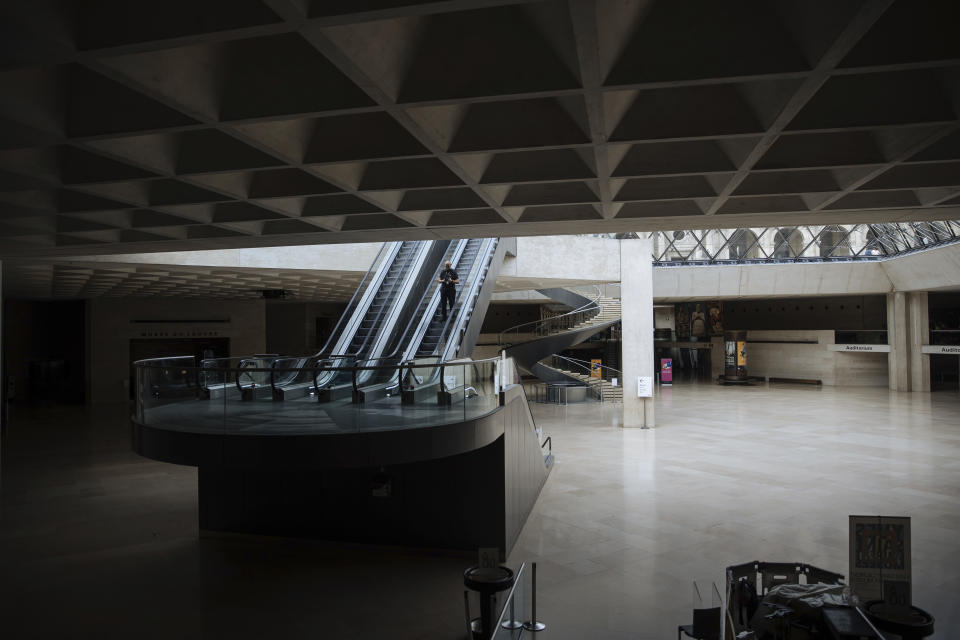 A man goes down the stairs inside the empty central hall of the Louvre Museum, in Paris, Tuesday, July 26, 2022. The museum benefits from one of Paris' best-kept secrets, an underground cooling system that's helped the Louvre cope with the sweltering heat that has broken temperature records across Europe. (AP Photo/Lewis Joly)