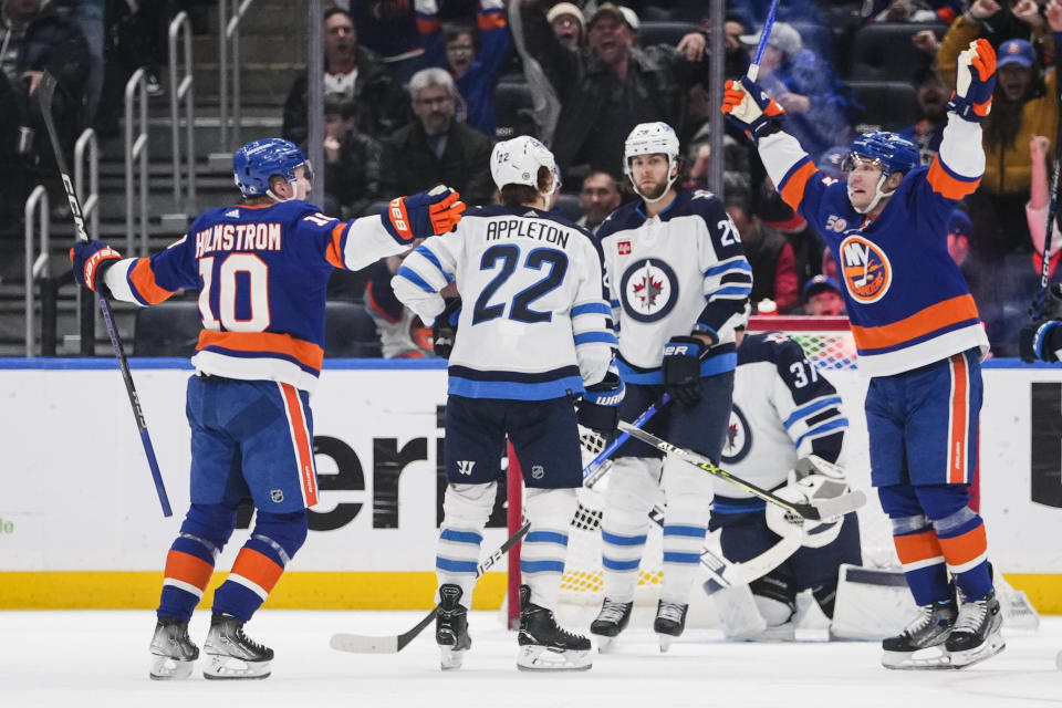 Winnipeg Jets' Kevin Stenlund (28) watches New York Islanders' Bo Horvat and Simon Holmstrom (10) celebrate after Holmstrom scored a goal during the third period of an NHL hockey game Wednesday, Feb. 22, 2023, in Elmont, N.Y. The Islanders won 2-1. (AP Photo/Frank Franklin II)