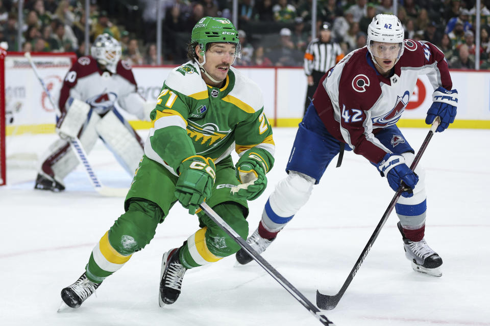 Minnesota Wild right wing Brandon Duhaime, left, and Colorado Avalanche defenseman Josh Manson (42) compete for the puck during the first period of an NHL hockey game Friday, Nov. 24, 2023, in St. Paul, Minn. (AP Photo/Matt Krohn)