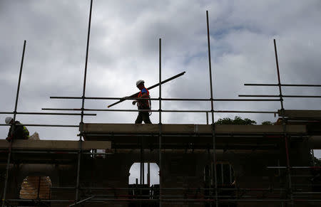 FILE PHOTO: A builder assembles scaffolding as he works on new homes, in south London June 3, 2014. REUTERS/Andrew Winning/File Photo