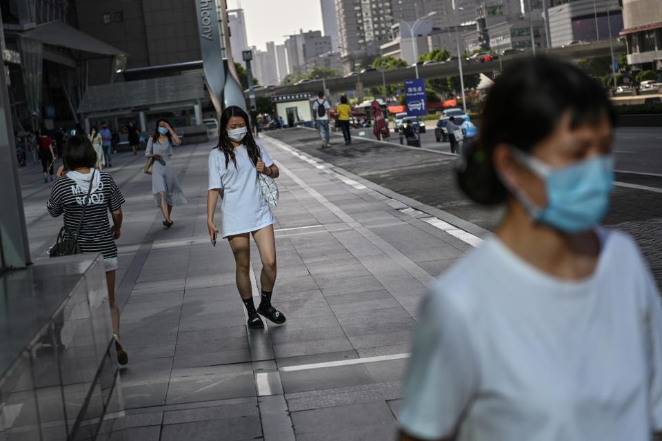 Women wearing a face mask walk in a street of Wuhan, in Chinas central Hubei province on May 18, 2020. - Authorities in the pandemic ground zero city of Wuhan have ordered mass COVID-19 testing for all 11 million residents after a new cluster of cases emerged over the weekend. (Photo by Hector RETAMAL / AFP) (Photo by HECTOR RETAMAL/AFP via Getty Images)