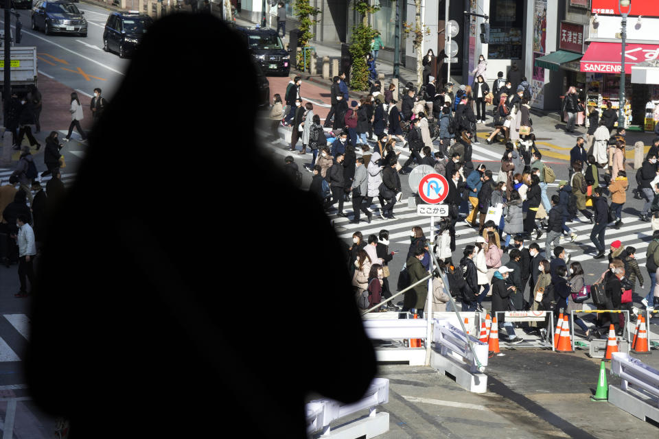 People wearing protective masks to help curb the spread of the coronavirus walk along a pedestrian crossing Friday, Jan. 21, 2022, in Tokyo. Restaurants and bars will close early in Tokyo and a dozen other areas across Japan beginning Friday as the country widens COVID-19 restrictions due to the omicron variant causing cases to surge to new highs in metropolitan areas. (AP Photo/Eugene Hoshiko)