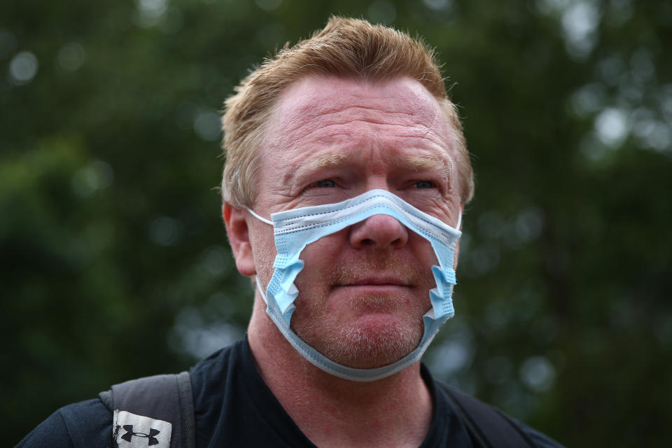 Un opositor al uso de mascarillas con un cobrebocas recortado a modo de protesta. (Photo by Hollie Adams/Getty Images)