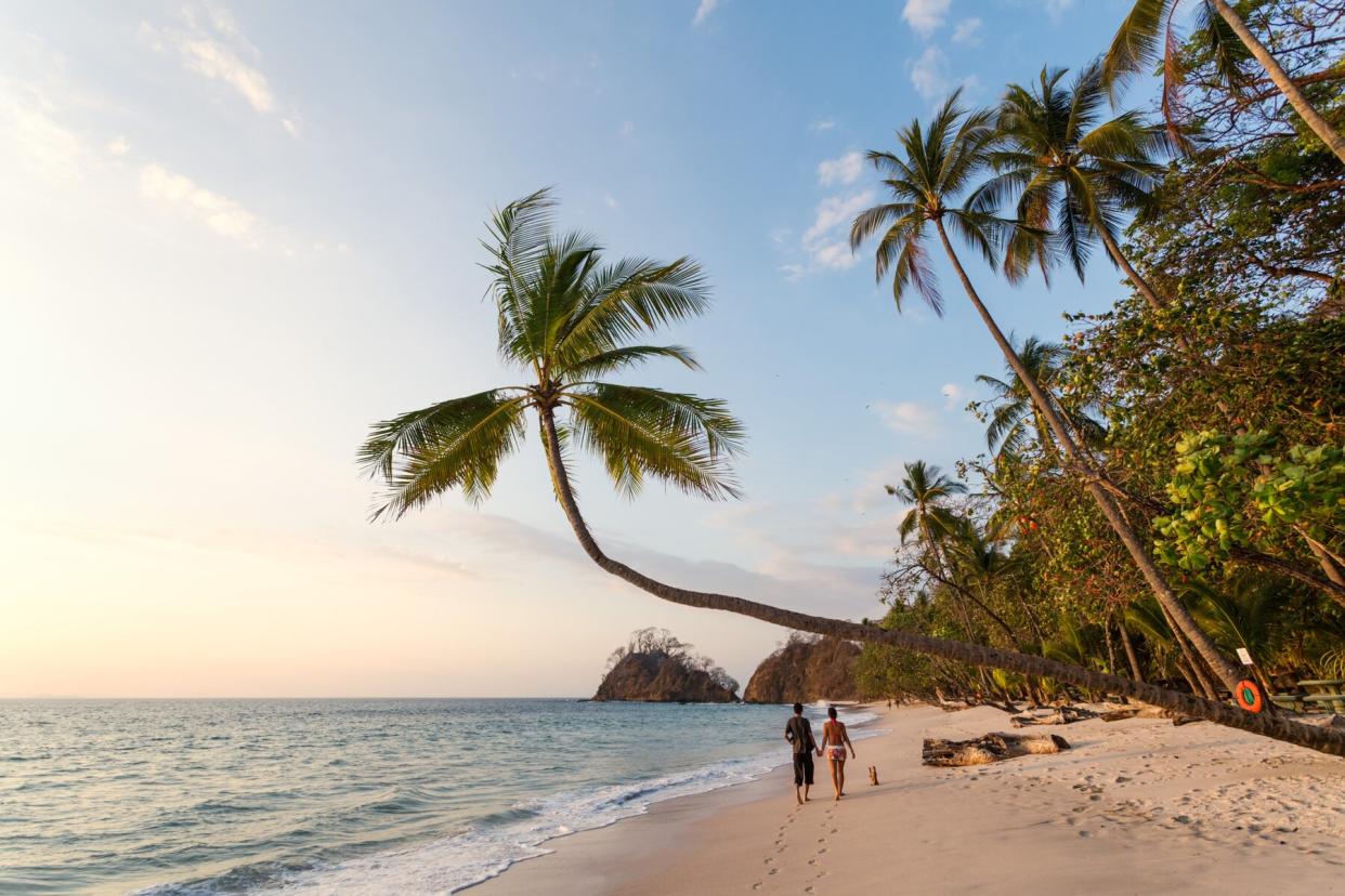 Couple of tourists walking on beach at sunset, Costa Rica