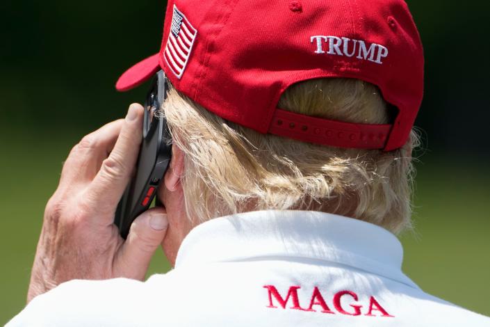 Former President Donald Trump takes a call on the driving range before the second round of the LIV Golf at Trump National Golf Club, Saturday, May 27, 2023, in Sterling, Va.