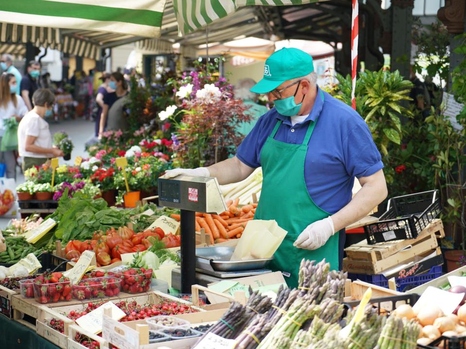 A man standing at a booth at a farmer's market in Turin, Italy