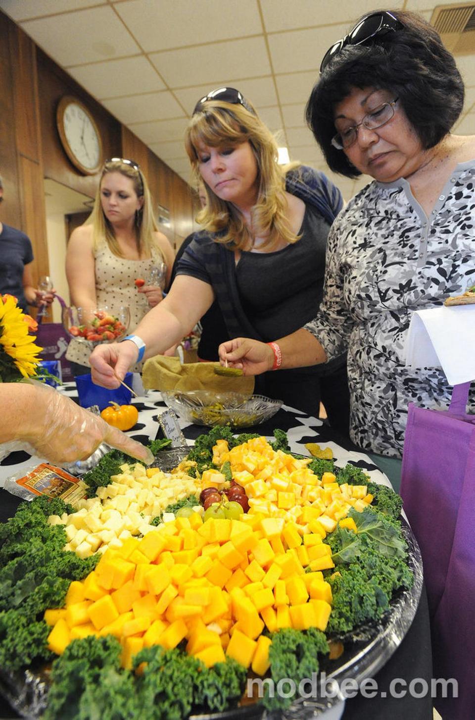 Modesto’s Helen Merrick (right) chooses between a variety of cheeses including a Beehive honey cheese, Cajun dusted, Coffee cheese, cheddar, cooly’s, and jack’s, during the Riverbank Cheese and Wine exposition 2013 Saturday evening (10-12-13) in downtown Riverbank.