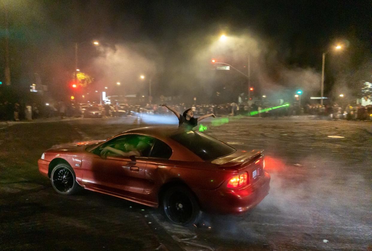 A person leans out of a car during a street takeover