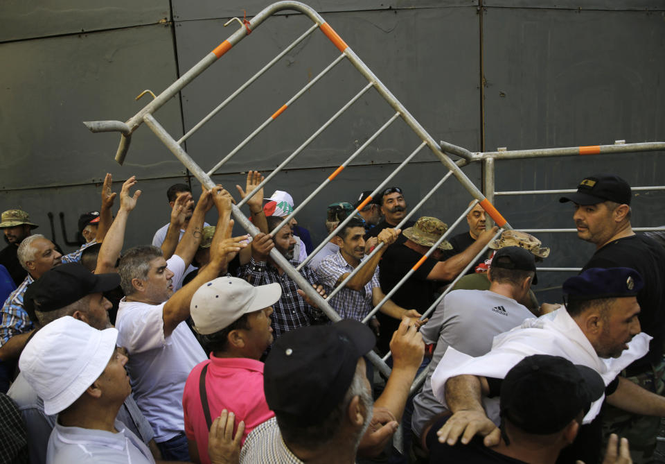 Lebanese retired soldiers, remove barriers installed to block a road linked to the parliament, as they try to enter the parliament building where lawmakers and ministers are discussing the draft 2019 state budget, in Beirut, Lebanon, Friday, July 19, 2019. The budget is aimed at averting a financial crisis in heavily indebted Lebanon. But it was met with criticism for failing to address structural problems. Instead, the budget mostly cuts public spending and raises taxes. (AP Photo/Hussein Malla)