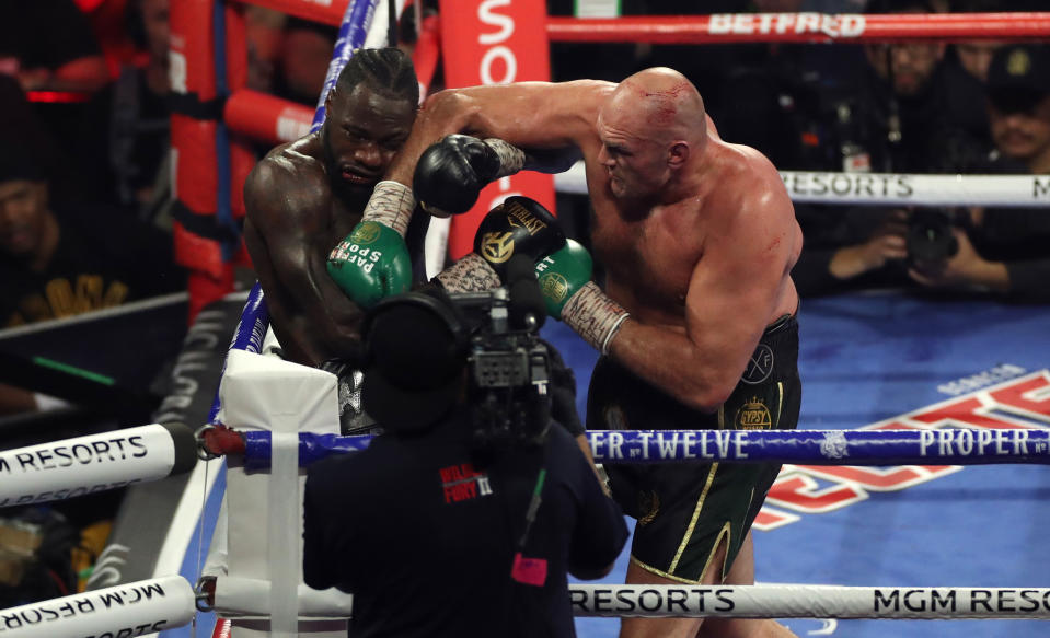 Tyson Fury (right) and Deontay Wilder punch each other.