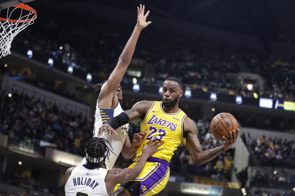 Los Angeles Lakers forward LeBron James (23) makes a pass as he's defended by Indiana Pacers guard Aaron Holiday (3) and center Myles Turner (33) during the first half of an NBA basketball game in Indianapolis, Tuesday, Dec. 17, 2019. (AP Photo/Michael Conroy)