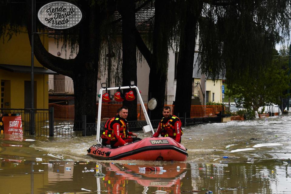 Volunteer firefighters ride their dinghy across a street flooded by the river Savio in the Ponte Vecchio district of Cesena, central eastern Italy, on May 17, 2023. Trains were stopped and schools were closed in many towns while people were asked to leave the ground floors of their homes and to avoid going out, and multiple people have died after the floods across Italy's northern Emilia Romagna region.