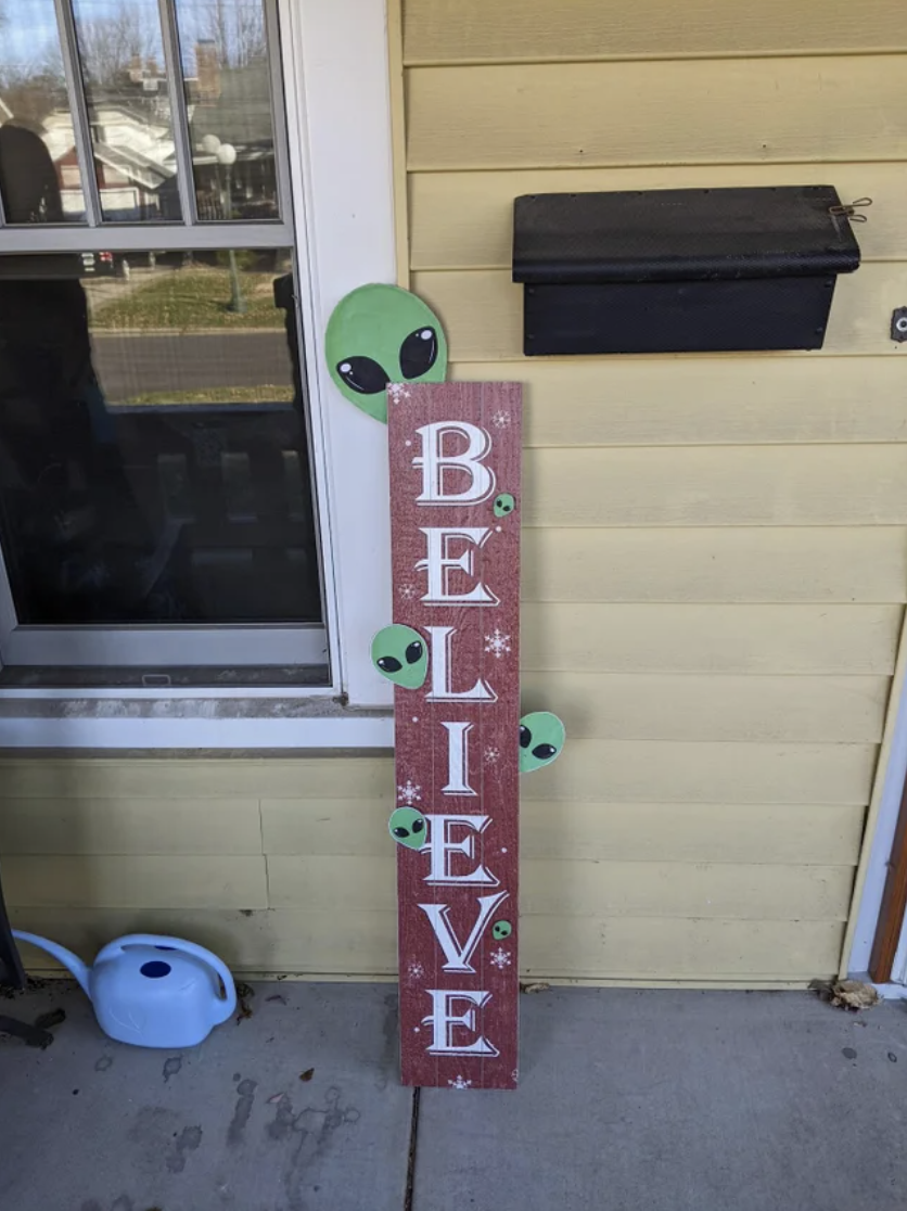 alien heads on a believe sign