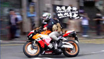 FILE - In this Wednesday, July 1, 2020, file image made from video, motorcyclist Tong Ying-kit carries a flag reading "Liberate Hong Kong, Revolution of our times" during a protest in Hong Kong on the anniversary of its return to China. Tong has been sentenced to nine years in prison in the closely watched first case under Hong Kong’s national security law as Beijing tightens control over the territory. (Cable TV Hong Kong via AP)