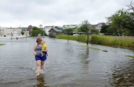 Vacationer Sharon Cornwell of Tennessee carries her eight-month-old son Riley Copcutt, through a flooded street after Hurricane Arthur passed through in Manteo, North Carolina July 4, 2014. REUTERS/Chris Keane