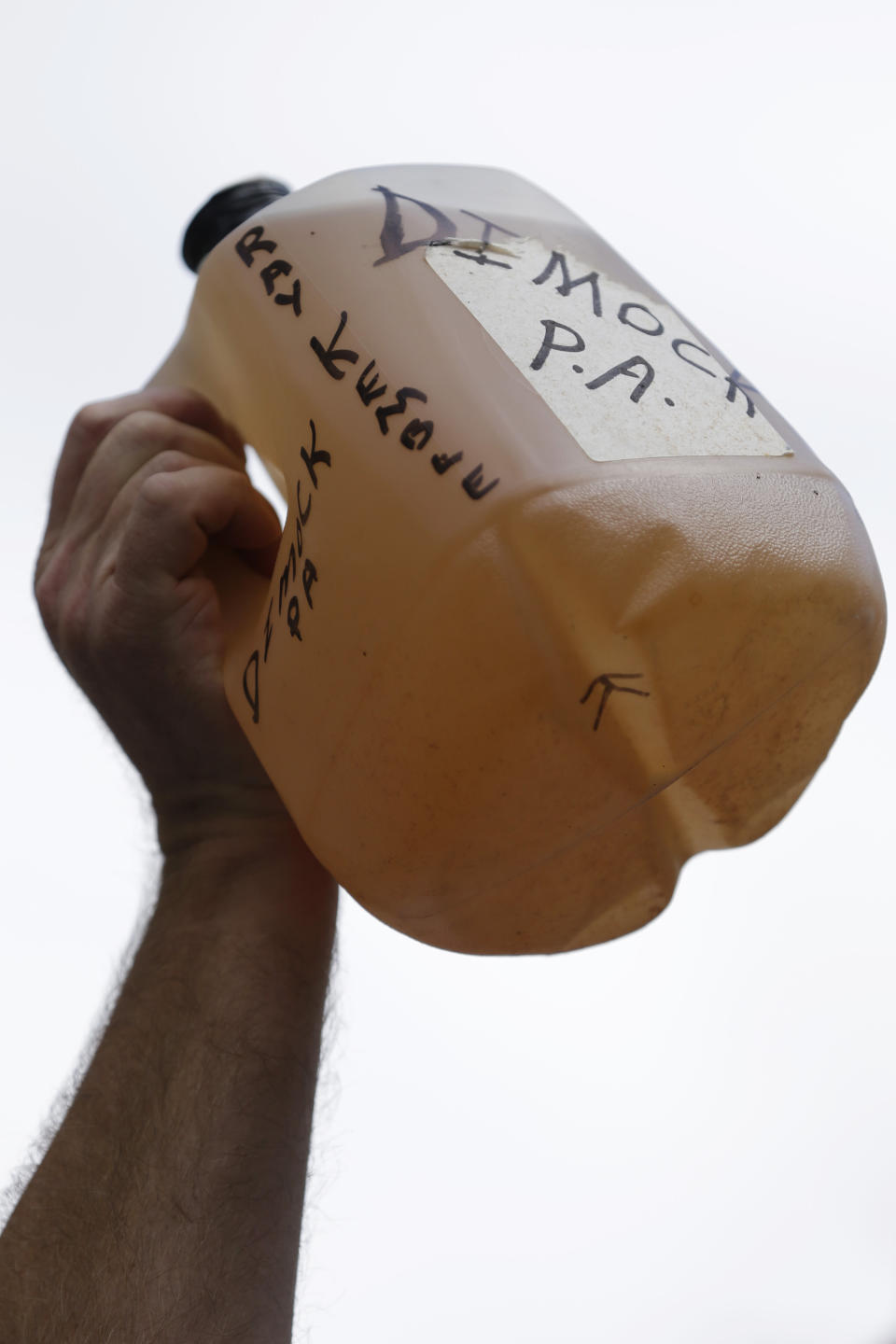 FILE - Ray Kemble of Dimock, Pa., protests hydraulic fracturing outside a Marcellus Shale industry conference as he holds a jug of well water, on Sept. 20, 2012, in Philadelphia. Residents of Dimock, a rural community whose drinking water has been contaminated for 14 years met, Monday, Nov. 21, 2022, with high-level officials in the Pennsylvania attorney general’s office, a clear indication of movement in the state’s long-running criminal case against a gas driller charged with polluting the aquifer. (AP Photo/Matt Rourke, File)