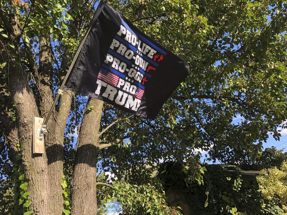 A flag supporting former President Donald Trump flies outside a Lovettsville, Va., home, on Oct. 23, 2021. America's divisions are apparent in the northern Virginia town, where banners of the right and the left mark the community's polarization. But in Lovettsville and places like it across U.S., neighborly ways and social ties persist as well, under the radar of a country that seems at war with itself a year after the Jan. 6 insurrection at the U.S. Capitol. (AP Photo/Cal Woodward)