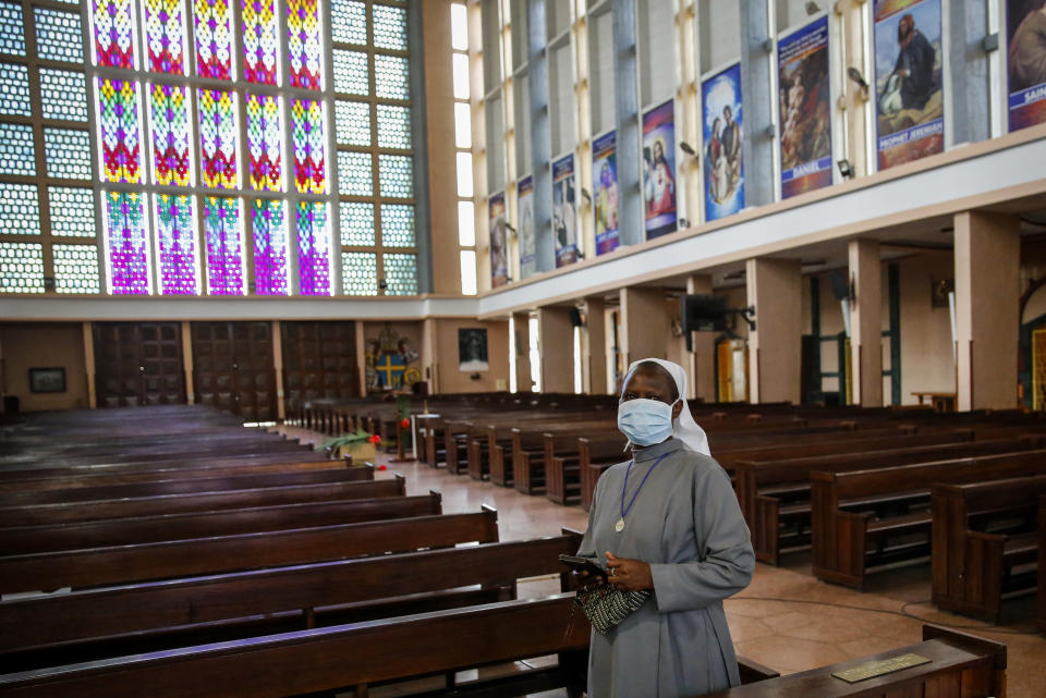 A Catholic nun wearing a face mask, to curb the spread of the new coronavirus, walks inside the the empty Holy Family Minor Basilica cathedral after a Palm Sunday mass that was broadcast on television but had no congregation attending, in Nairobi, Kenya Sunday, April 5, 2020. The new coronavirus causes mild or moderate symptoms for most people, but for some, especially older adults and people with existing health problems, it can cause more severe illness or death. (AP Photo/Brian Inganga)